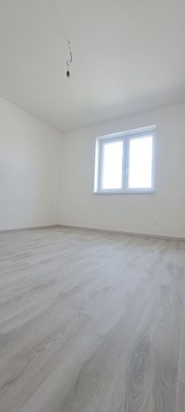 Pokoj s oknem a podlahou s dřevěným dekorem v rodinném domě.