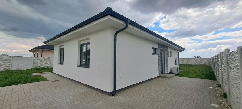 Rodinný dům v Topoľnici s bílou fasádou a dlážděnou terasou.