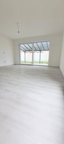 Interiér rodinného domu s velkým oknem a podlahou s dřevěným dekorem.