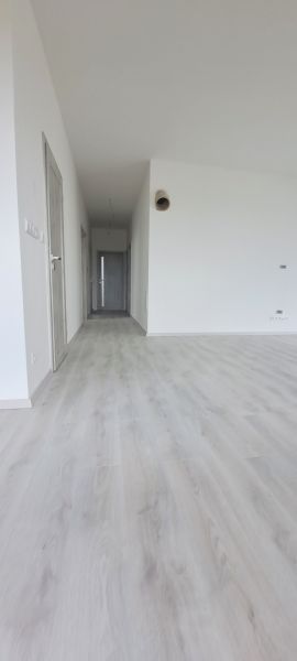 Interiér rodinného domu s bílými stěnami a podlahou s dřevěným dekorem.