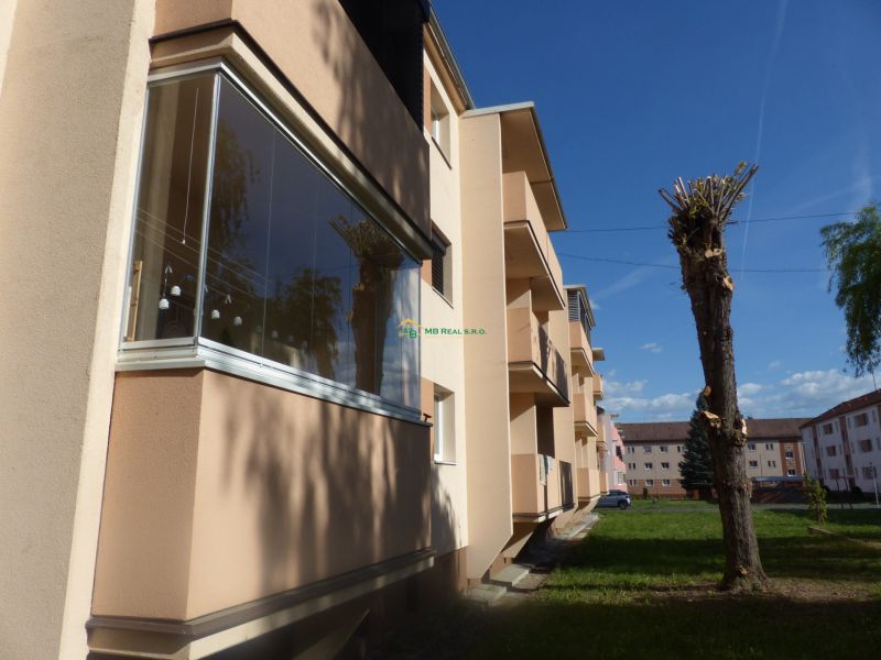 Bytový dům s balkony a upravenými stromy v Žiaru nad Hronom, vhodný pro 2-pokojový byt.