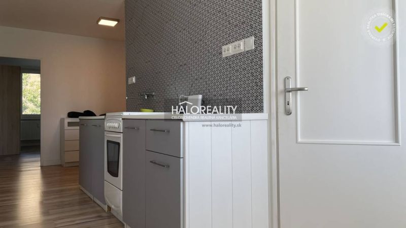 Kuchyně s laděním šedých skříněk a podlahou s dřevěným dekorem v 2pokojovém bytě.