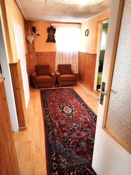 Rodinný dům se starožitným kobercem, podlahou s dřevěným dekorem a oranžovými stěnami.