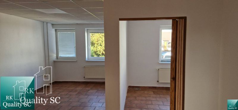 Interiér rodinného domu s terakotovou podlahou, bílými stěnami a radiátory pod okny.