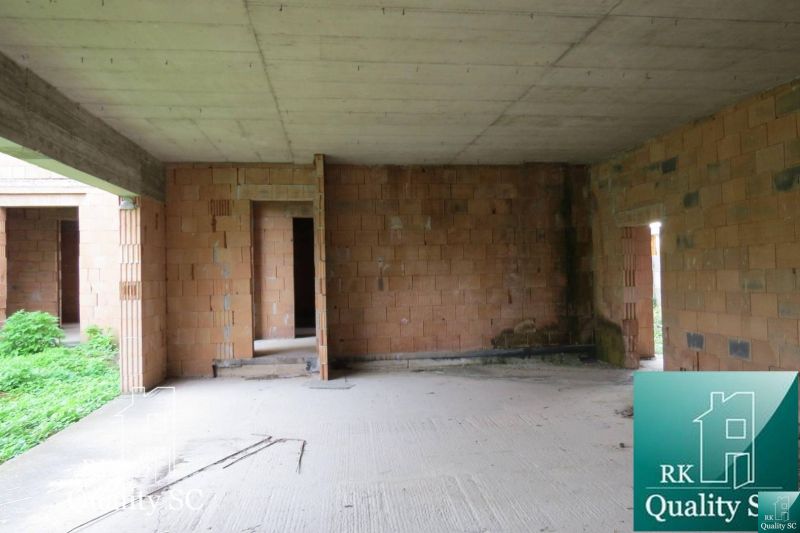 Interiér rodinného domu s cihlovými stěnami a betonovou podlahou, vhodný k úpravě.