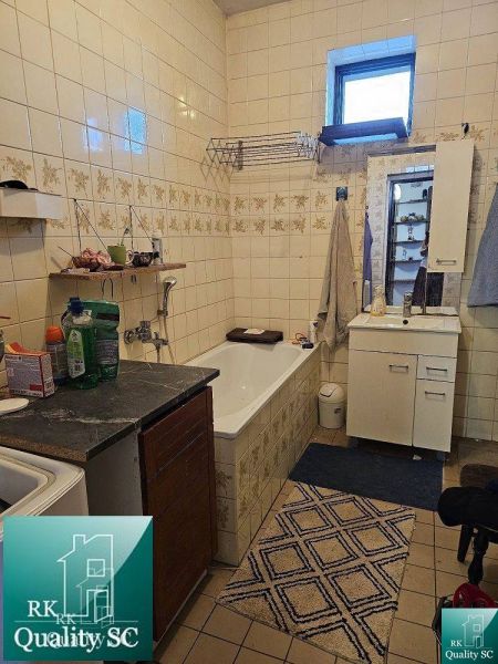 Koupelna v rodinném domě s vanou, umyvadlem a úložnými skříňkami. Kachličkované stěny.
