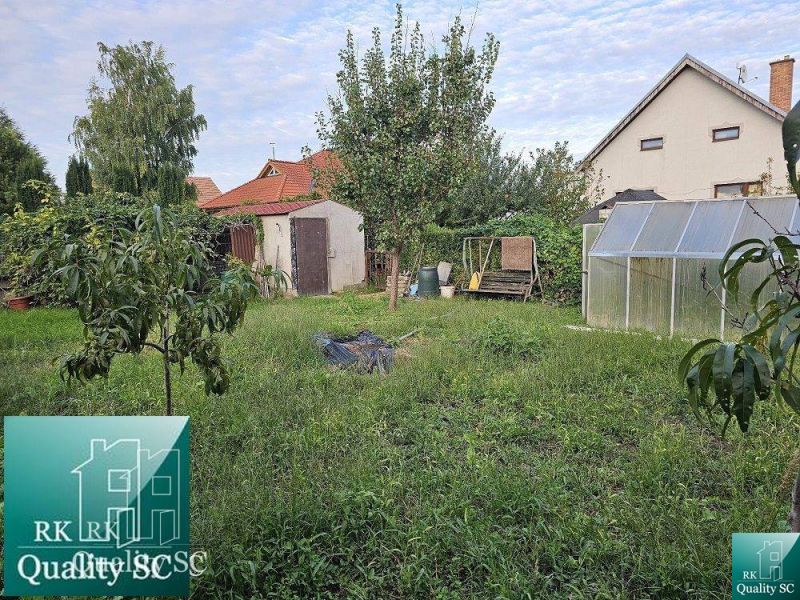 Zahrada s ovocnými stromy a skleníkem u rodinného domu na ulici v Tureň.