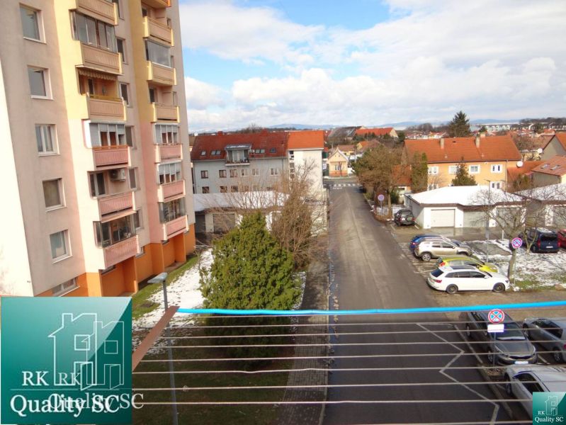 Pohled z 1-pokojového bytu na Náměstí 1. máje v Senci, ulice a parkoviště.