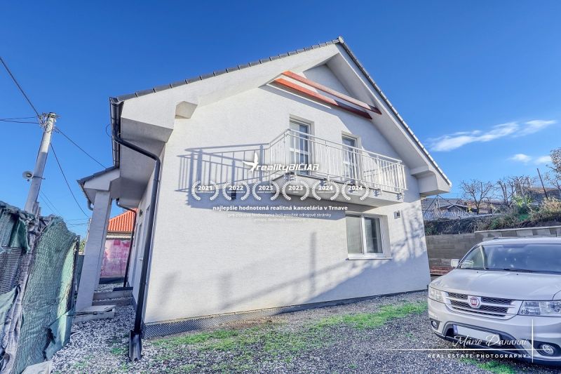 Rodinný dům v Hrnčiarovcích nad Parnou s bílou fasádou a balkonem na kamínkovém dvoře.