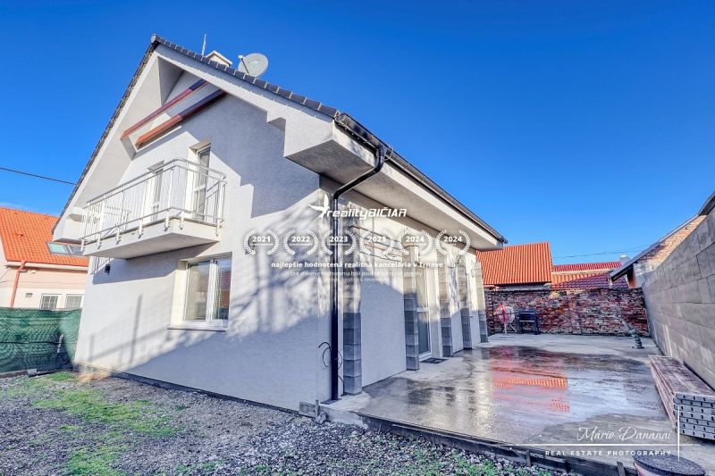 Rodinný dům v Hrnčiarovcích nad Parnou s betonovou terasou a balkonem v patře.
