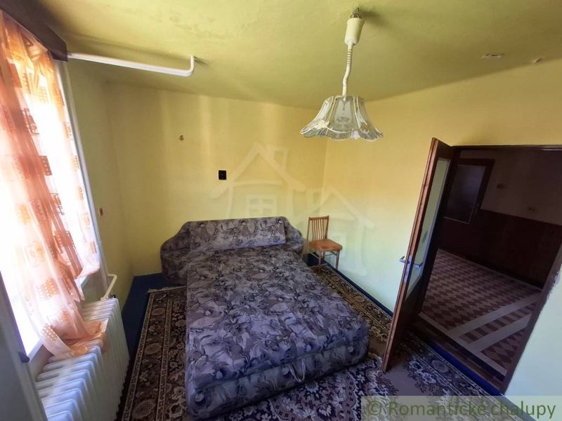 Pokoj s pohovkou, židlí, kobercem a závěsy. Stylový interiér rodinného domu.