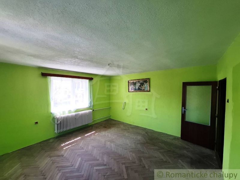 Zelené stěny a podlaha s dřevěným dekorem v rodinném domě, se slunečními paprsky přes okno.