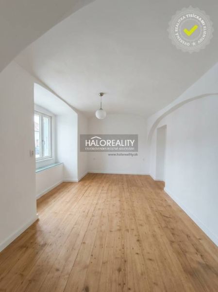 Světlý pokoj s klenutým stropem a podlahou s dřevěným dekorem v 3-pokojovém bytě.