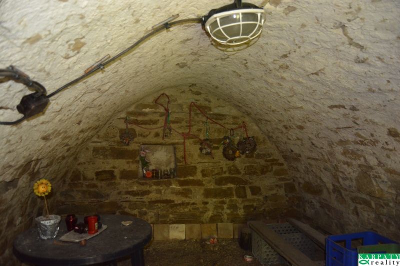 Kamenný sklep v rodinném domě s klenutým stropem a drobnou dekorací.