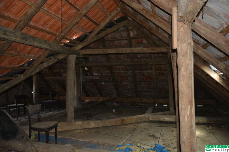 Podkroví rodinného domu s dřevěnými trámy, ideální na rekonstrukci a úložný prostor.