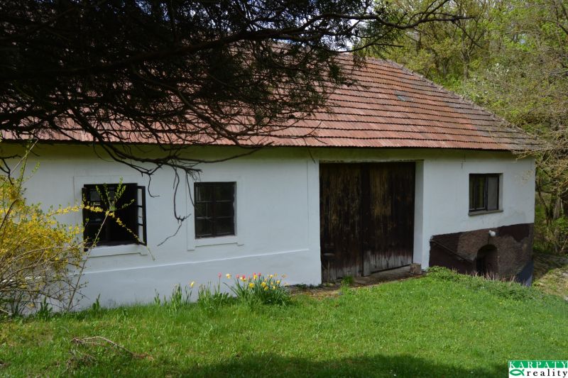 Rodinný dům v Bukovci se šikmou střechou a dřevěnými branami.