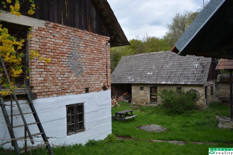 Rodinný dům v Bukovci s tradičními cihlovými a kamennými stavbami, zahradní stůl.