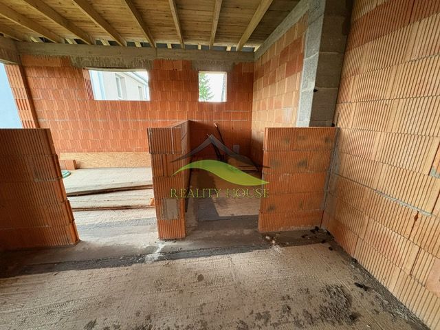 Interiér rodinného domu ve fázi výstavby s pohledem na cihly a strop.