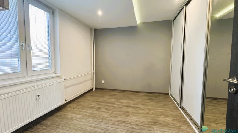 Prázdný pokoj se skříní a podlahou s dřevěným dekorem ve 4pokojovém bytě.