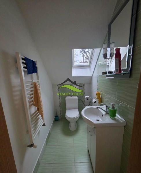Koupelna v rodinném domě se střešním oknem a zelenými obklady.