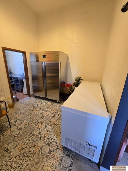 Chladicí místnost s dlažbou v gastro prostorech, obsahující kovovou skříň a mrazničku.