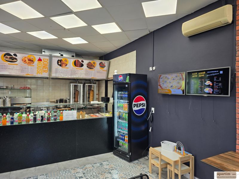 Gastro prostory s prodejem nápojů a jídel, podlaha s dřevěným dekorem, menu na stěnách.