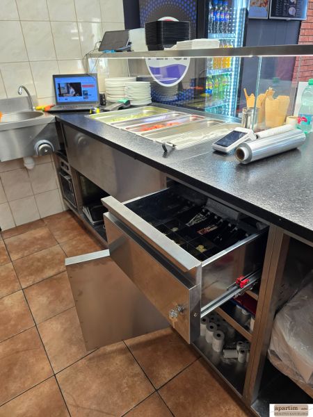 Kuchyňská linka v gastro prostorech s nerezovým vybavením a pokladnou.