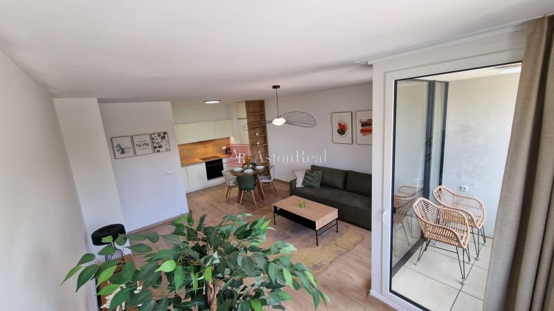 Interiér 2-pokojového bytu s podlahou s dřevěným dekorem, moderním nábytkem a balkonem.