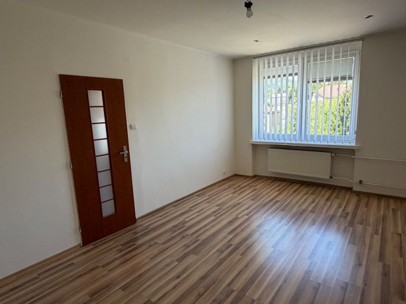 Pokoj v 1-pokojovém bytě s podlahou s dřevěným dekorem a velkým oknem.