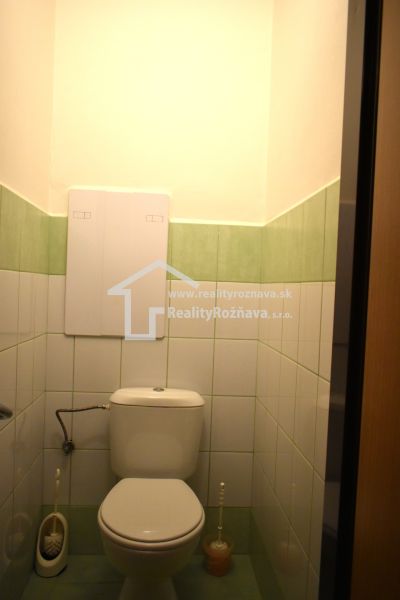 Koupelna se zeleno-bílými obklady a toaletou ve 3-pokojovém bytě.