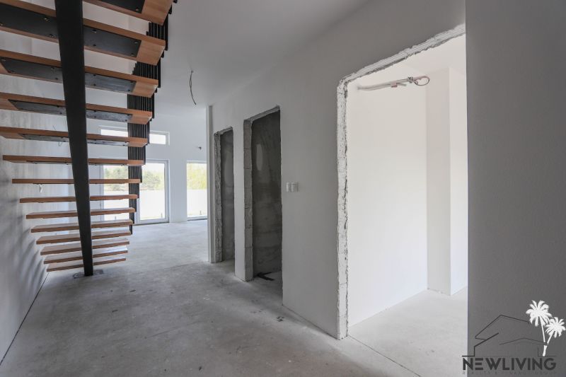 Interiér 4-pokojového bytu se schodištěm a velkými okny, neutrální barvy stěn.