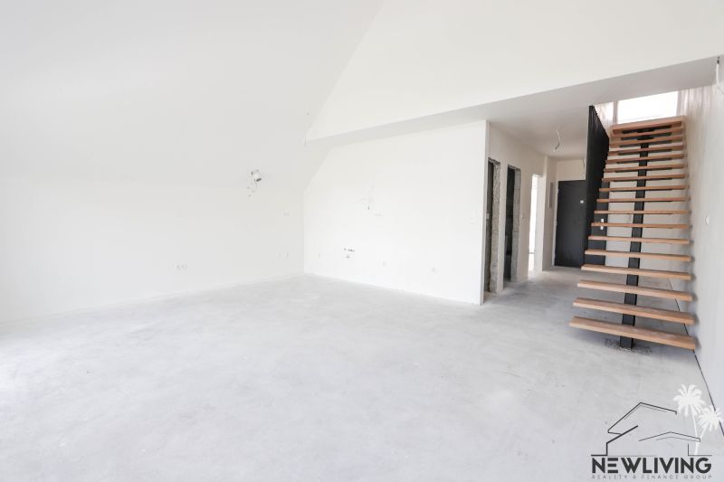 Interiér 4-pokojového bytu s betonovou podlahou a dřevěným schodištěm.