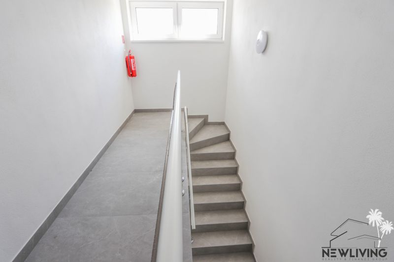 Schodiště s jednoduchým zábradlím a okny ve 4pokojovém bytě.
