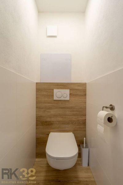 Minimalistická toaleta se závěsným WC a podlahou s dřevěným dekorem ve 4-pokojovém bytě.