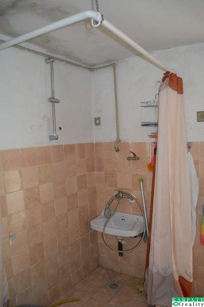Koupelna s dlažbou a závěsem v rodinném domě, jednoduché umyvadlo.