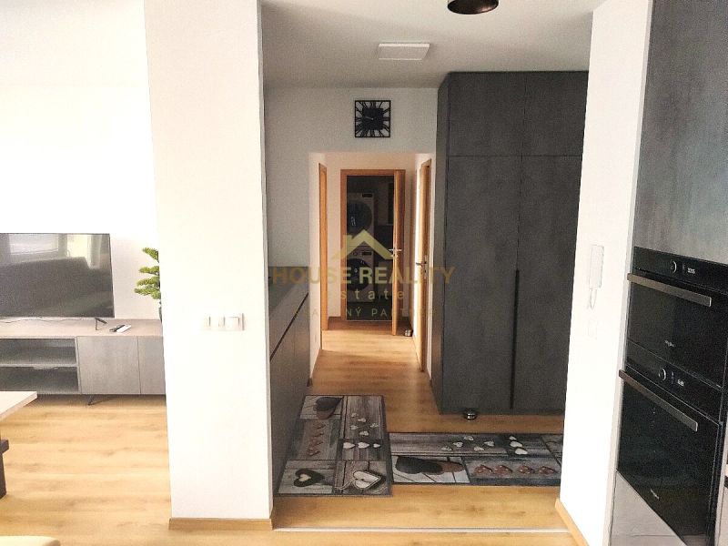 Interiér 2-pokojového bytu s podlahou s dřevěným dekorem, televizí a úložným prostorem.