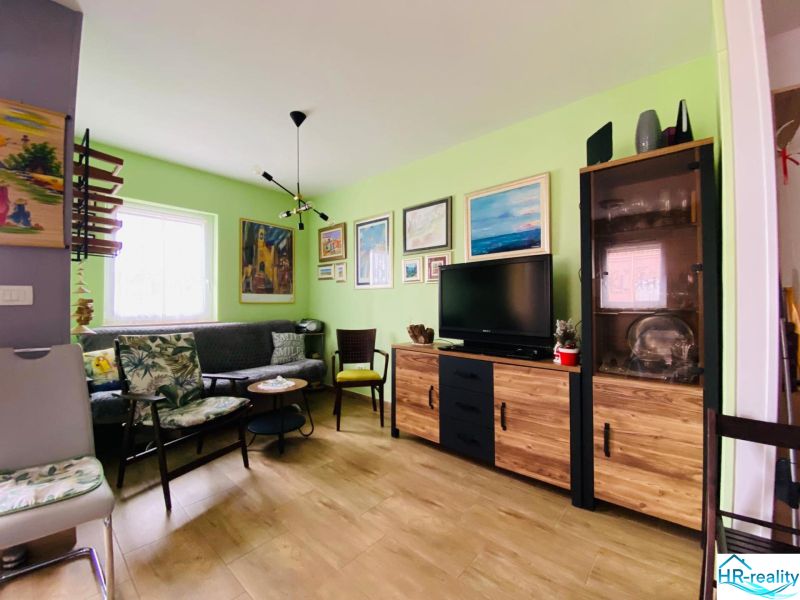 Obývací pokoj s pohovkou, televizorem a podlahou s dřevěným dekorem v Rekreačním apartmánu.