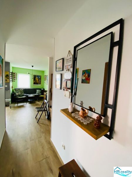 Chodba v rekreačním apartmánu s podlahou s dřevěným dekorem a zrcadlem na stěně.