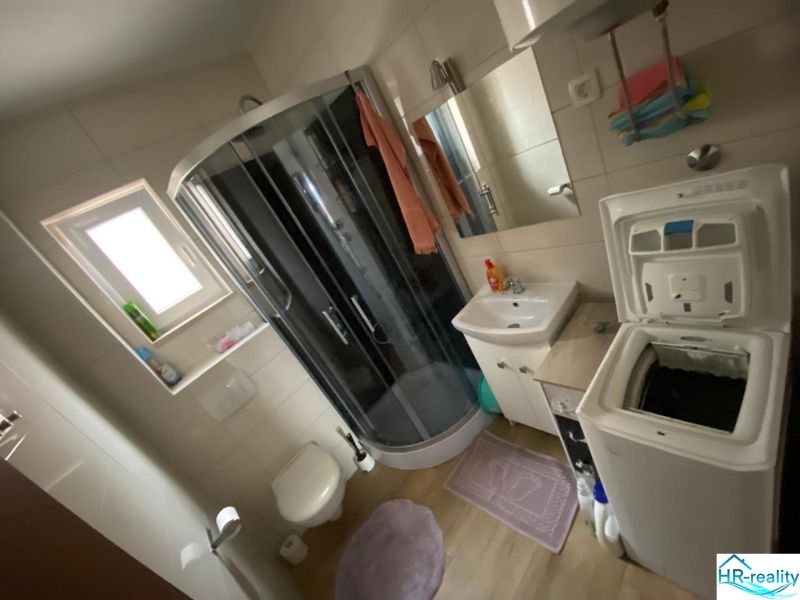 Koupelna v rekreačním apartmánu s pračkou, sprchovým koutem a umyvadlem.