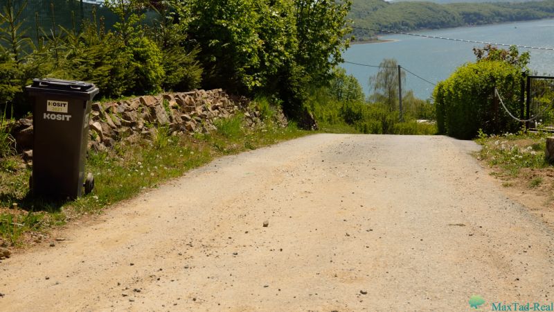 Zpevněná cesta, odpadkový koš a výhled na jezero v Nové Kelči, Rekreační pozemky.