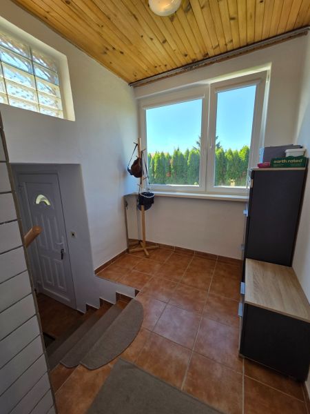 Chodba v rodinném domě s dřevěným stropem a keramickou dlažbou na podlaze.