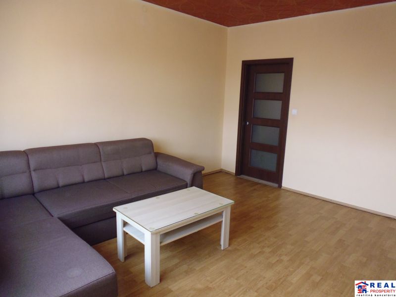 Světlý obývací pokoj s pohovkou a stolkem, podlaha s dřevěným dekorem.