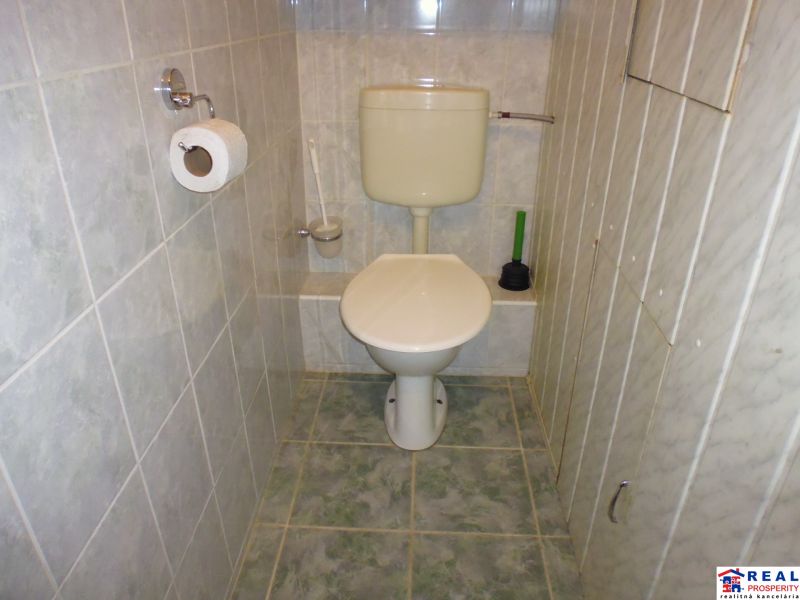 Koupelna s toaletou v 2-pokojovém bytě s kachličkovým obkladem a podlahou.