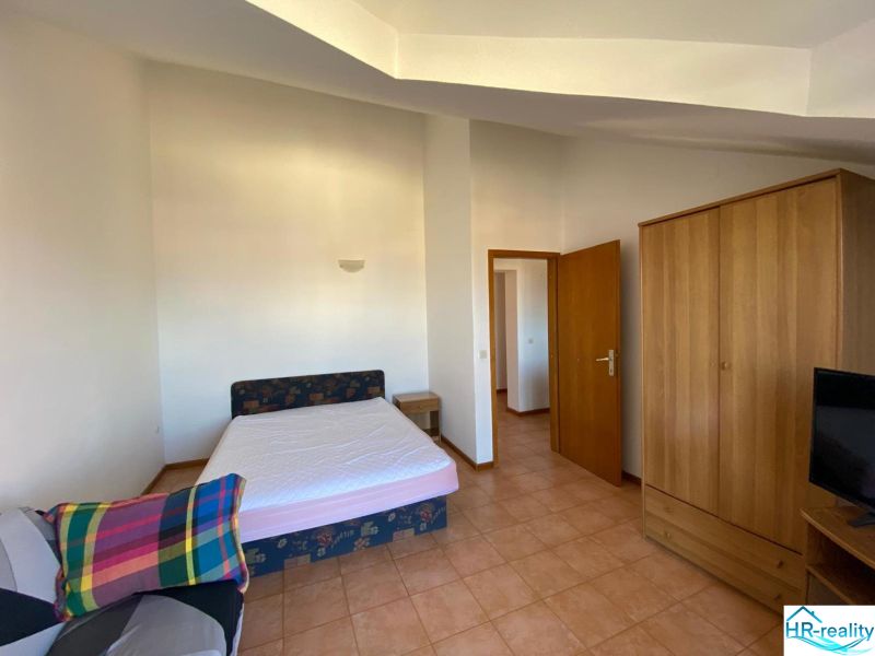 Ložnice v rekreačním apartmánu s postelí, skříní a televizorem.