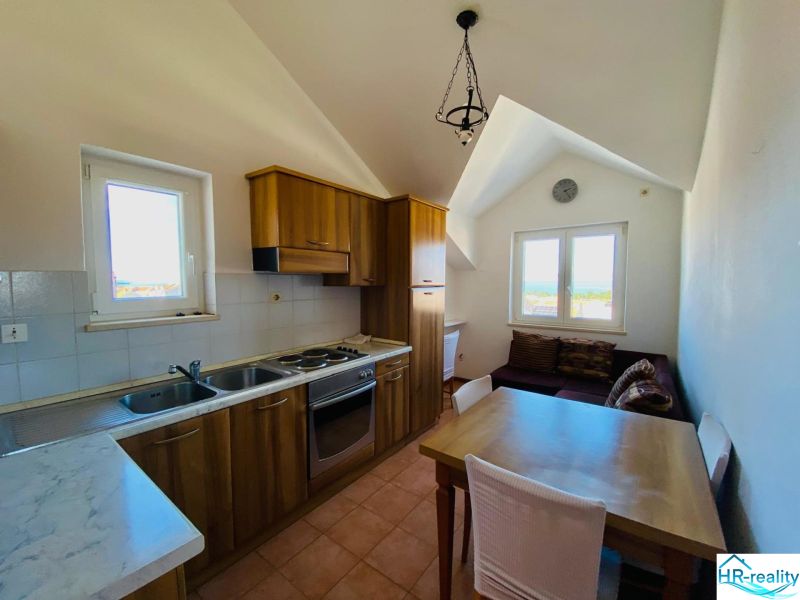 Kuchyně s dřevěným dekorem, jídelním stolem a pohovkou v rekreačním apartmánu.