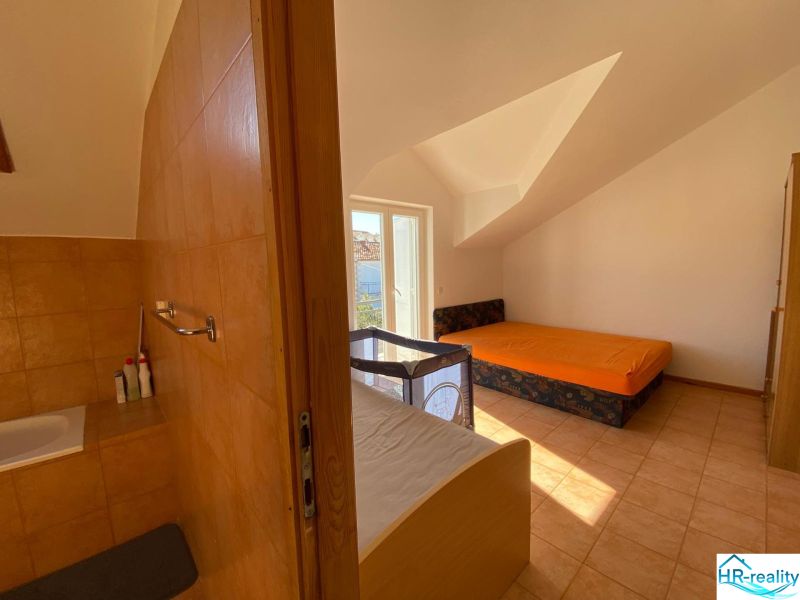 Interiér rekreačního apartmánu s pohovkou, postelí a dětskou postýlkou.