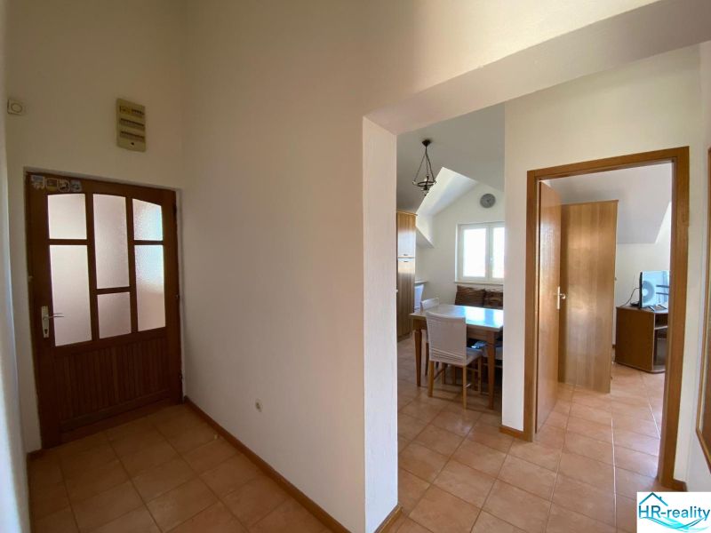 Chodba v rekreačním apartmánu s keramickou podlahou, jídelní kout a pokoj v pozadí.