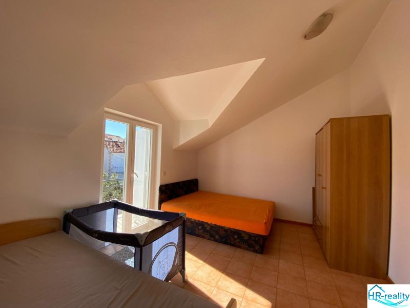 Ložnice v rekreačním apartmánu s postelemi, skříní a dětskou postýlkou.