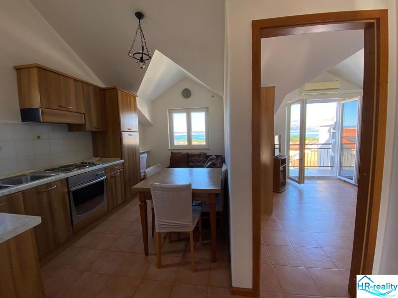 Kuchyně rekreačního apartmánu s dřevěnými skříňkami a výhledem na moře.