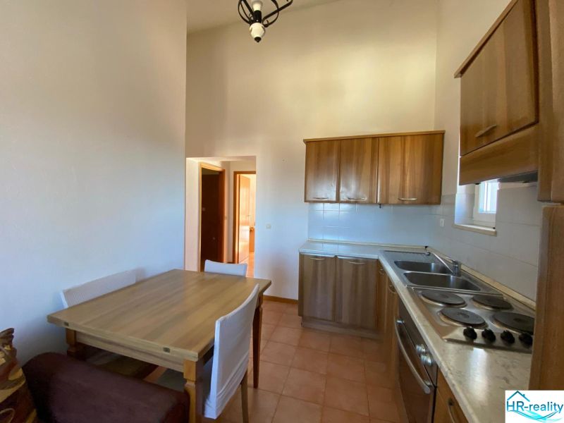 Kuchyně v rekreačním apartmánu s dřevěnými skříňkami a jídelním stolem.
